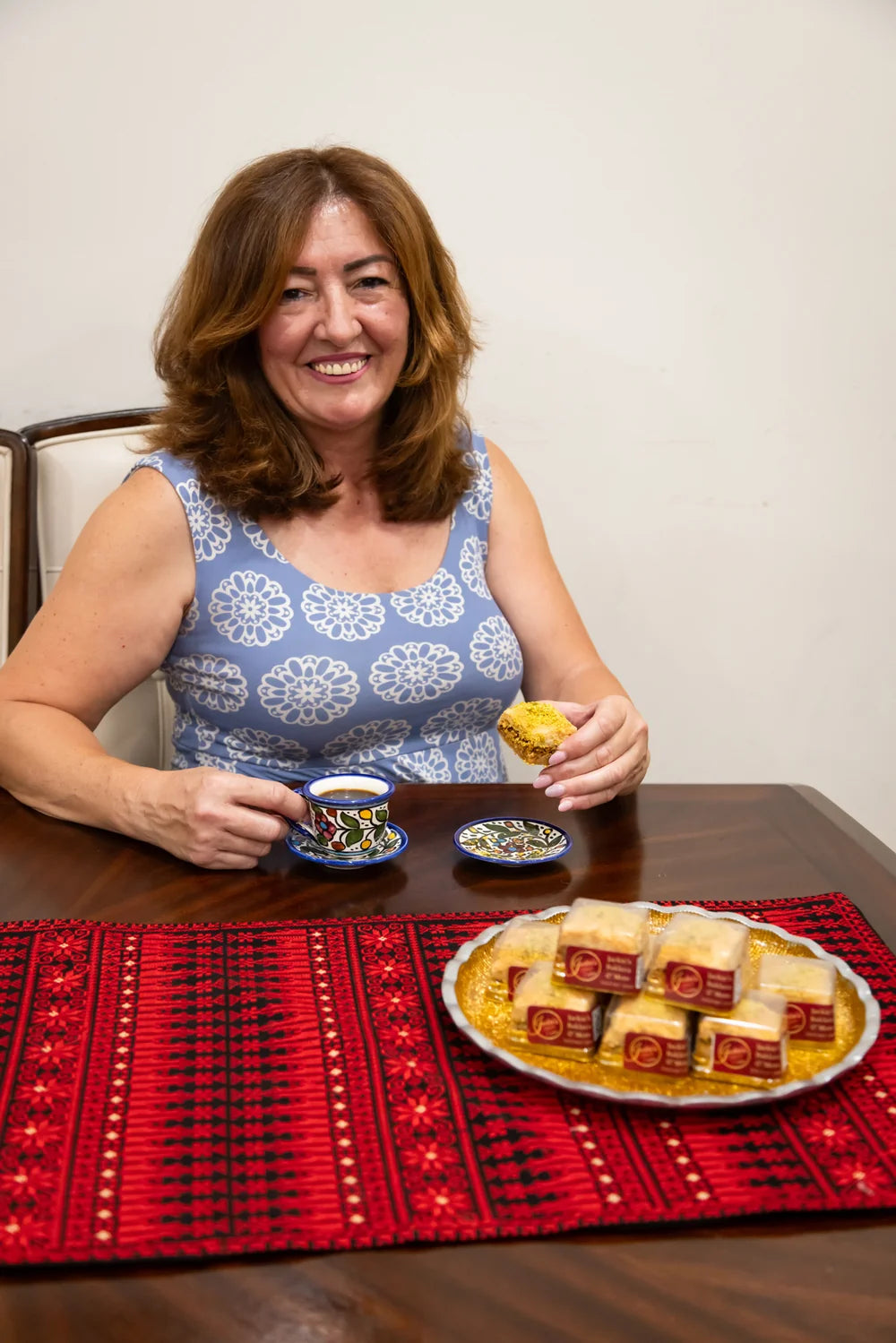 Jackie seated with coffee, baklava and a tray of packaged sweets.